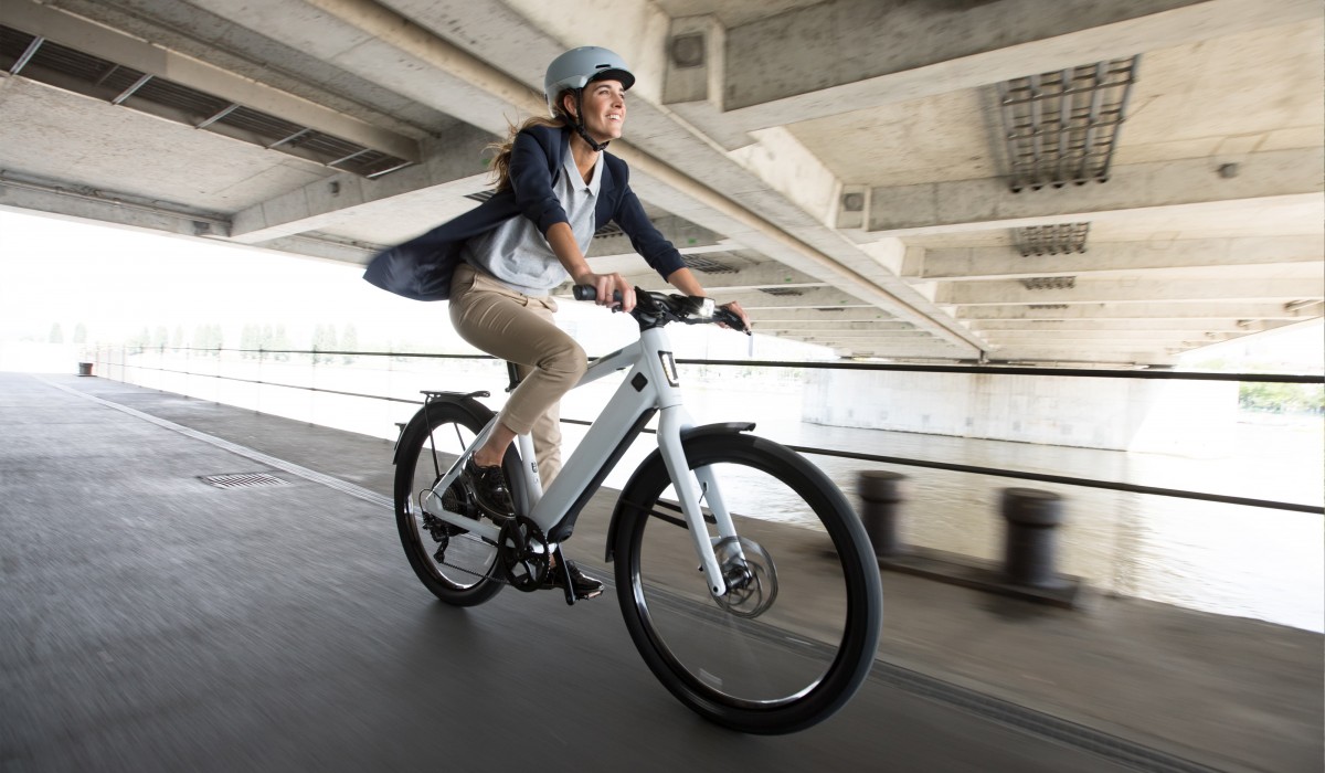 Get started with the Stromer leasing offers for employees: Woman riding her ST3 along the river.   